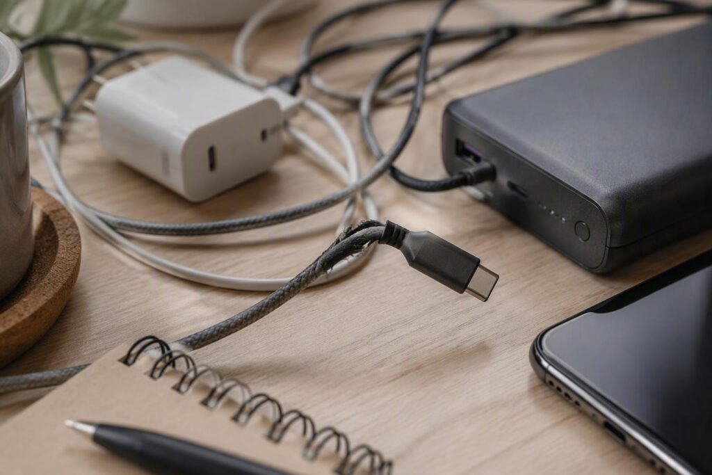 A phone, multi-port charger, USB-C cable and power bank arranged on a desk as a daily charging kit